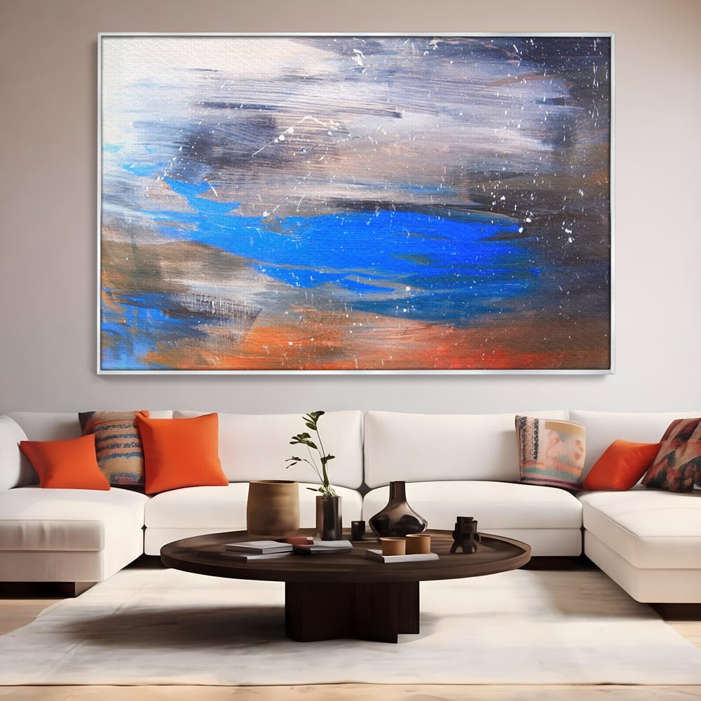Tablou canvas cu pictura abstracta cu pete albastre, in rama de aluminiu argintiu, pe perete intr-un living